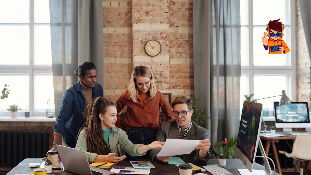 A group of four diverse professionals collaborating around a table in a modern, industrial-style office. One person is holding a document while others engage in discussion, surrounded by laptops, charts, and coffee cups. The scene highlights teamwork and the dynamic, fast-paced environment of digital marketing.