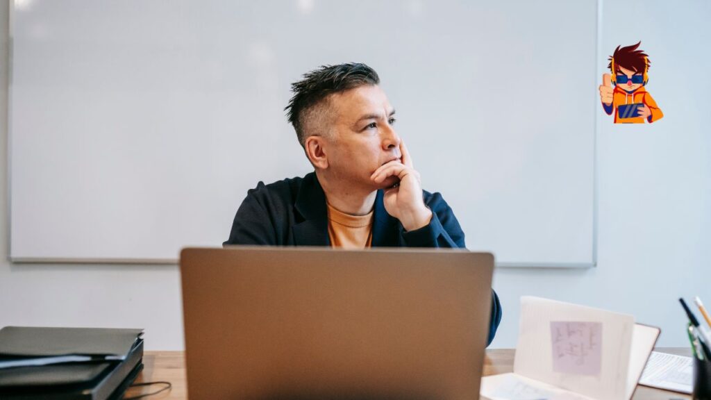 A person sitting at a desk with a laptop, gazing thoughtfully into the distance with a hand resting on their chin. The background features a whiteboard, symbolizing focus, deep thought, and a distraction-free work environment.